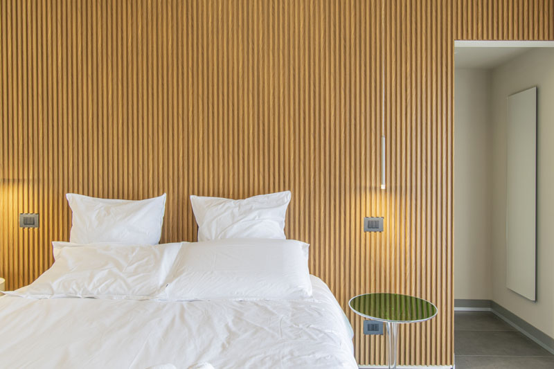 Letto matrimoniale davanti alla parete in legno a doghe — Camera ADA, Esse Elegant House