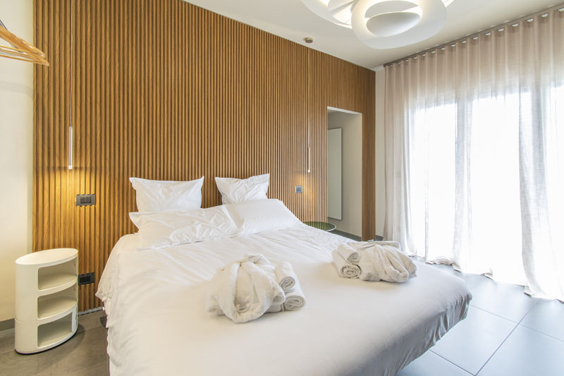 Letto matrimoniale con asciugamani arrotolati e comodini illuminati — Camera ADA, Esse Elegant House
